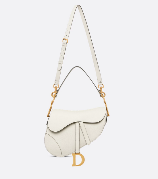White Dior handbag with gold accents on a light beige background