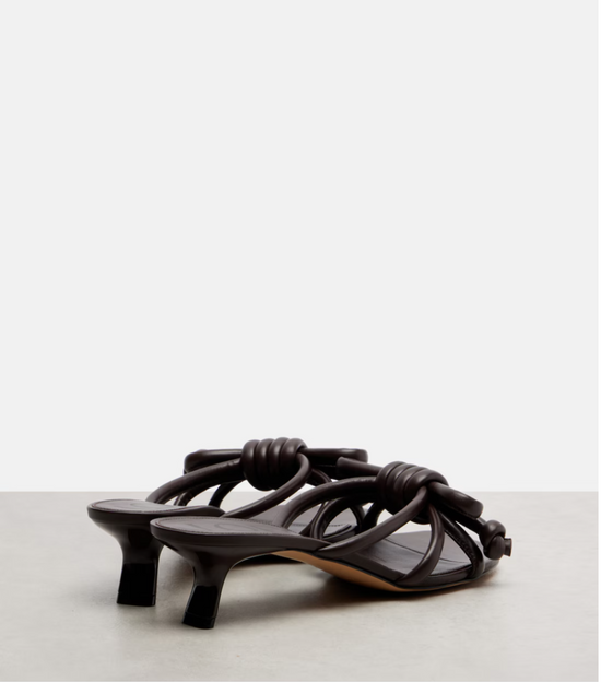Brown high-heeled sandals with knotted design on a light gray background
