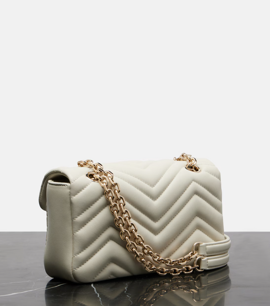 Gucci White quilted handbag with a gold chain on a reflective surface with a light gray background