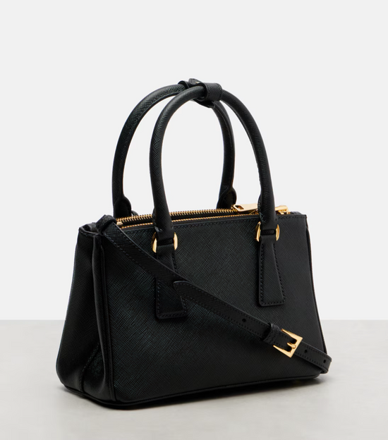 Black handbag with gold accents on a light gray background