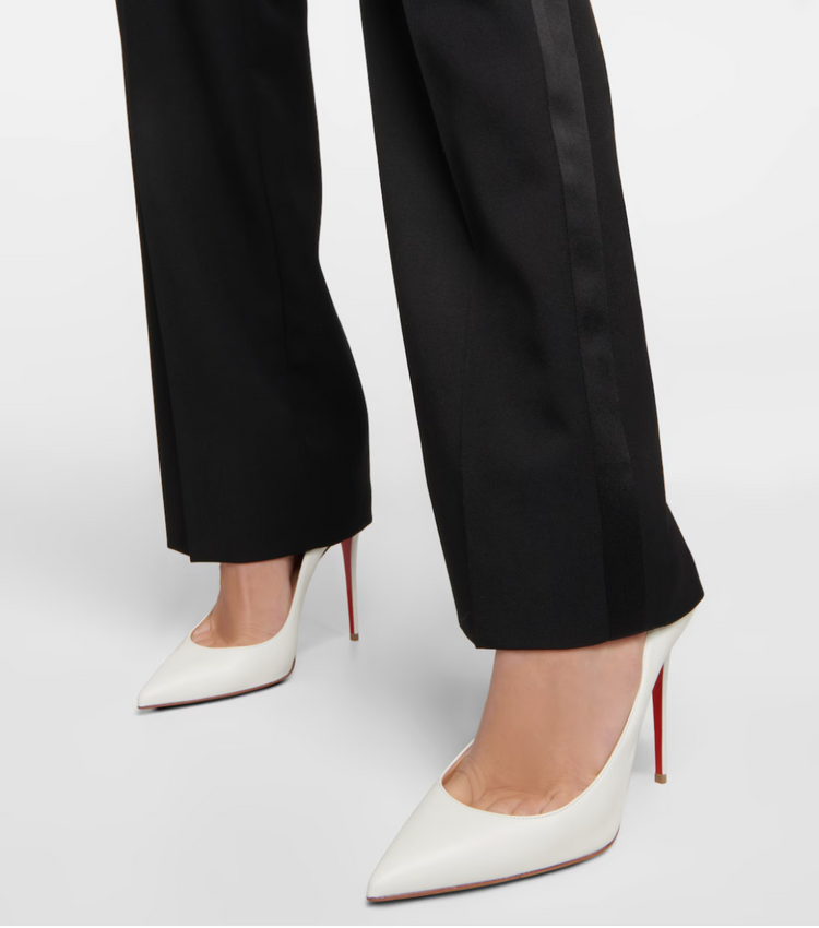 White high-heeled shoes worn with black pants on a white background