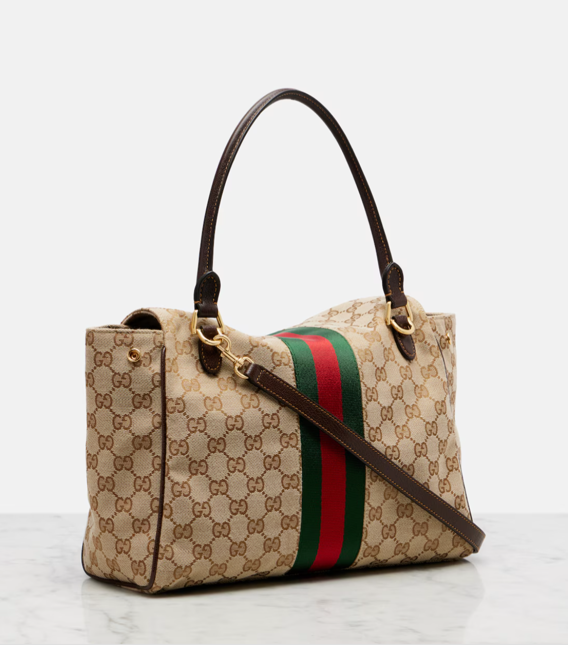 Designer handbag with monogram pattern and red and green stripe on a light background