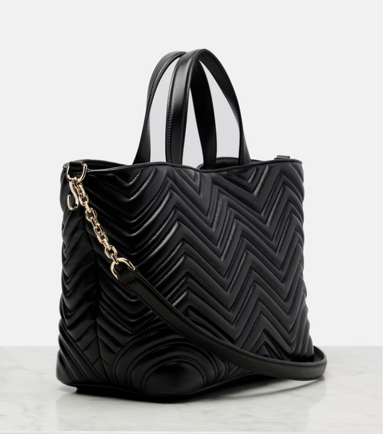 Black quilted handbag with a gold chain on a white background