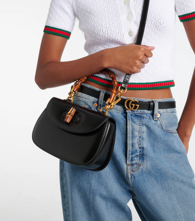 Person wearing a black Gucci handbag with a white background