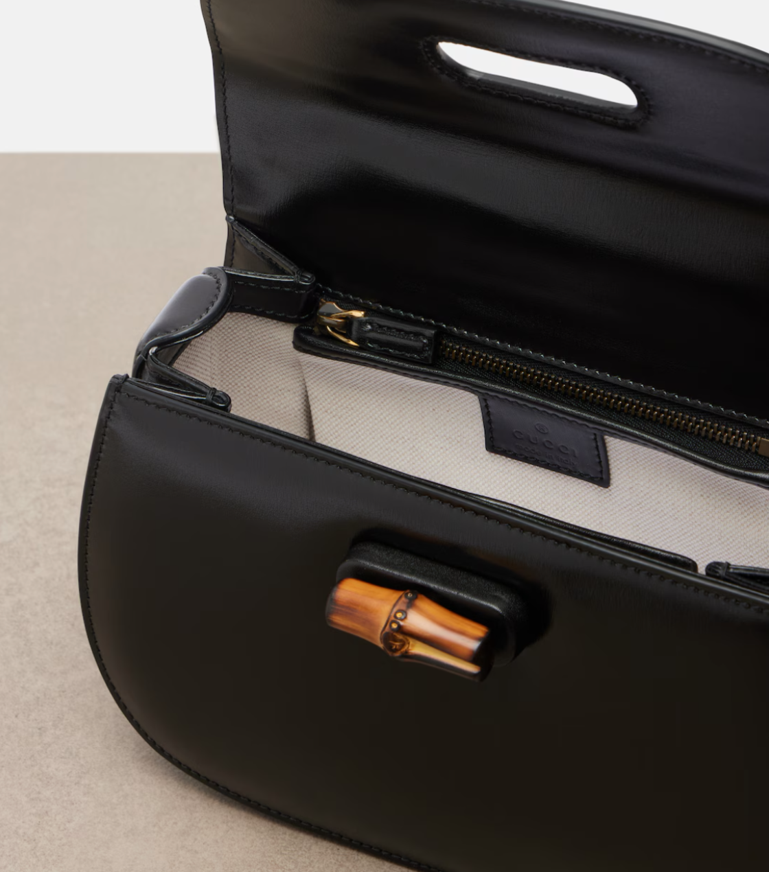 Black handbag with wooden handle on a beige surface