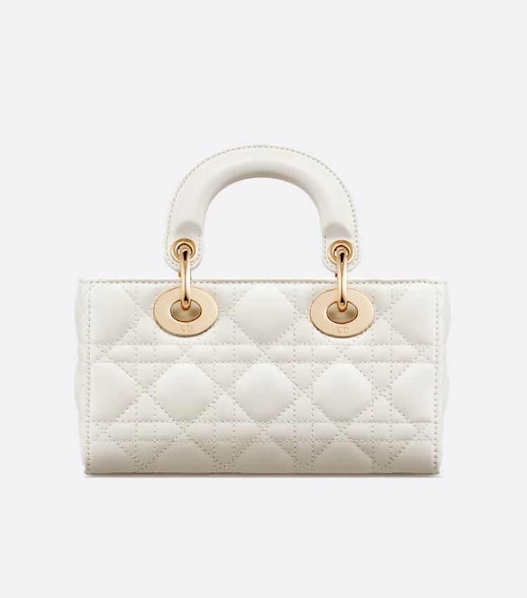 White quilted handbag with gold hardware on a light gray background