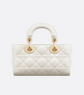 White quilted handbag with gold hardware on a light gray background