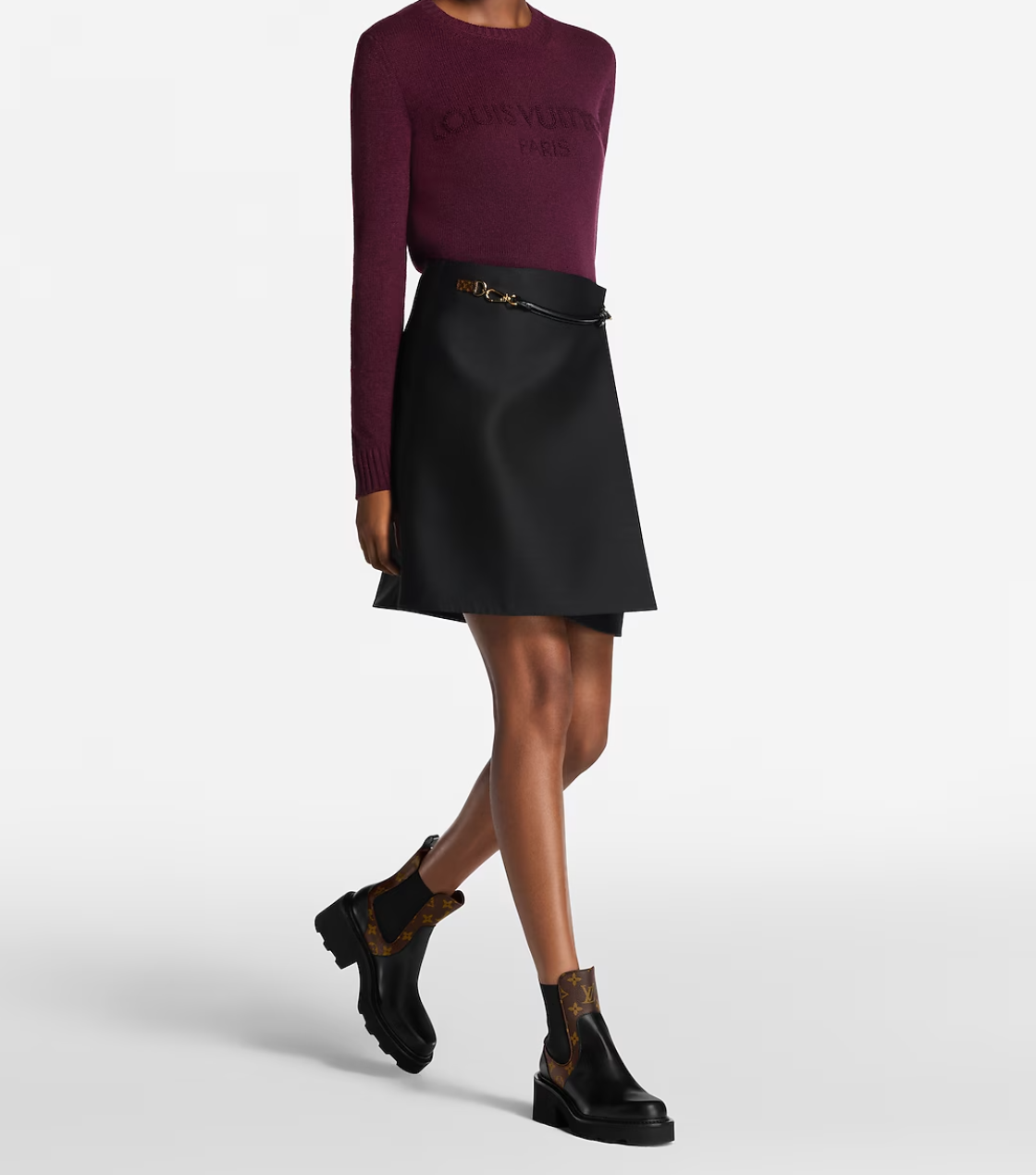 Person wearing a burgundy sweater and black skirt with black shoes on a white background
