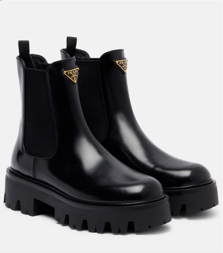 Black Chelsea boots with Prada logo on a white background