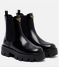 Black Chelsea boots with Prada logo on a white background