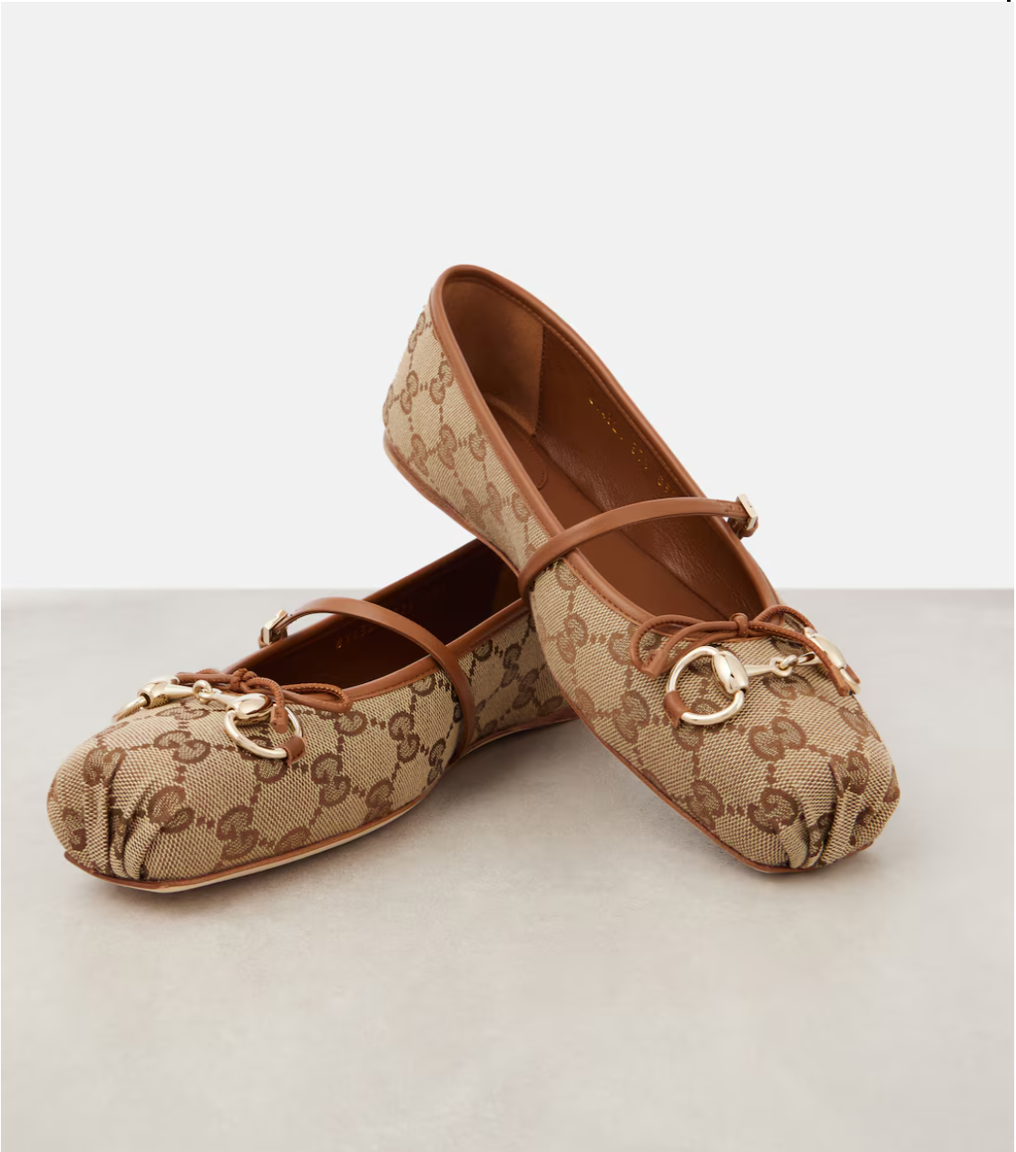Pair of brown patterned shoes with decorative elements on a light background