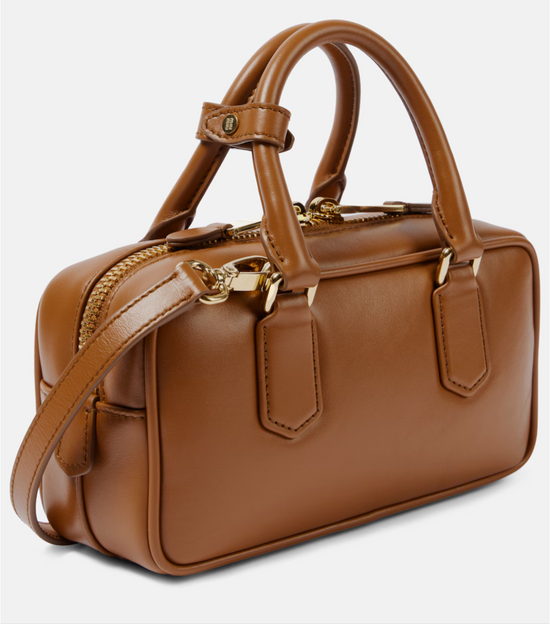 Brown leather handbag with gold accents on a light gray background