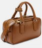 Brown leather handbag with gold accents on a light gray background