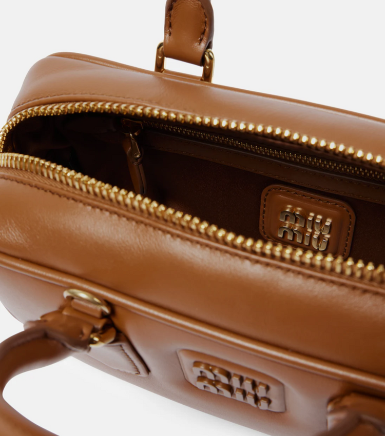 Brown leather handbag with gold zipper and handle on a white background