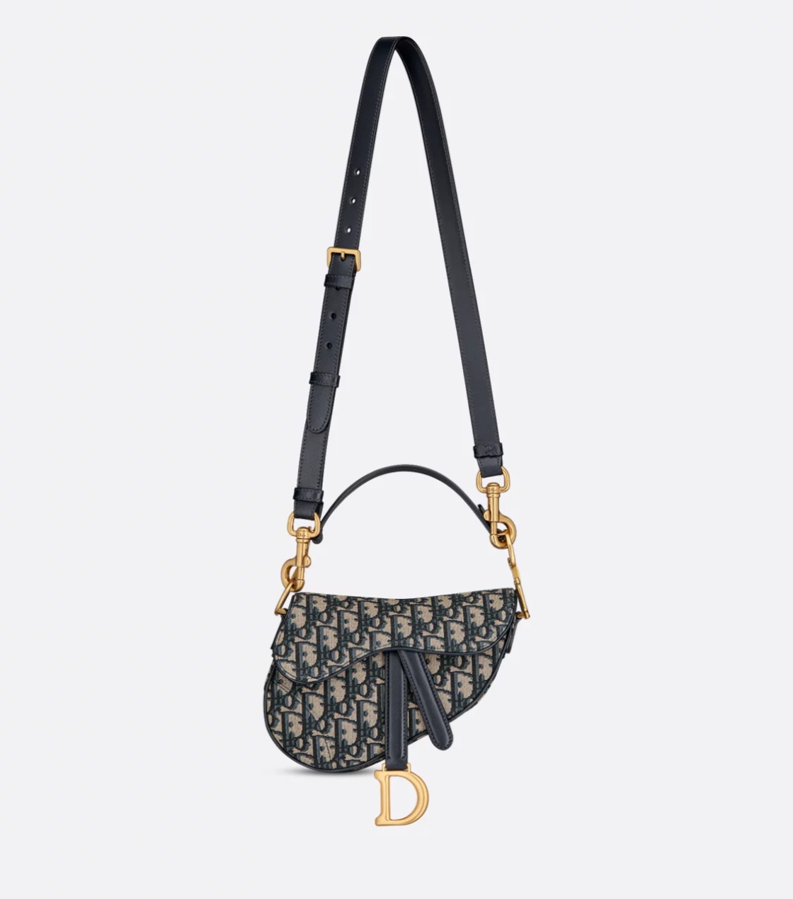 Designer handbag with black strap and gold hardware on a light gray background