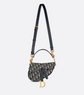 Designer handbag with black strap and gold hardware on a light gray background