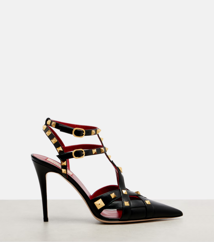 Black high-heeled shoe with gold accents on a white background