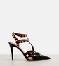 Black high-heeled shoe with gold accents on a white background