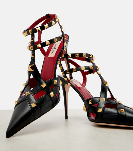Black high-heeled shoes with gold stud details on a white background