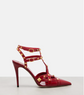 Red high-heeled shoe with gold accents on a light gray background