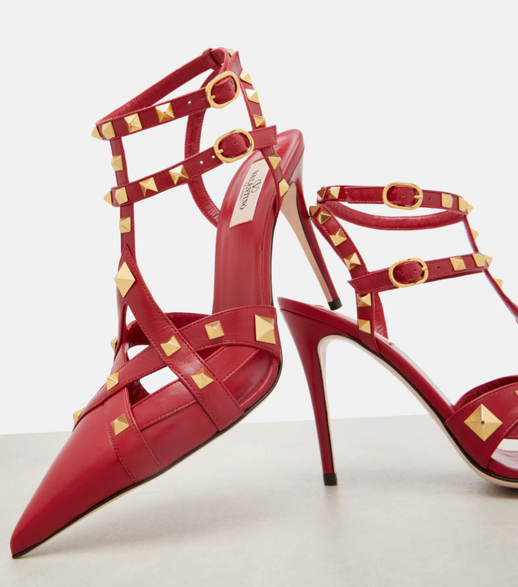 Red high-heeled shoes with gold accents on a light background