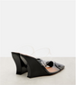 Black high-heeled shoes with clear plastic sole on a light gray background