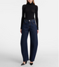 Person wearing dark blue jeans and a black turtleneck on a white background