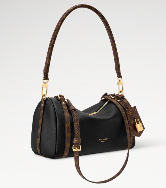 Black handbag with brown leather handle and strap on a white background