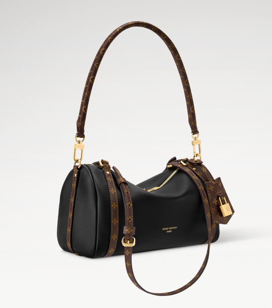 Black handbag with brown leather handle and strap on a white background