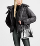 Person wearing a patterned jacket holding a transparent handbag with Louis Vuitton logo.