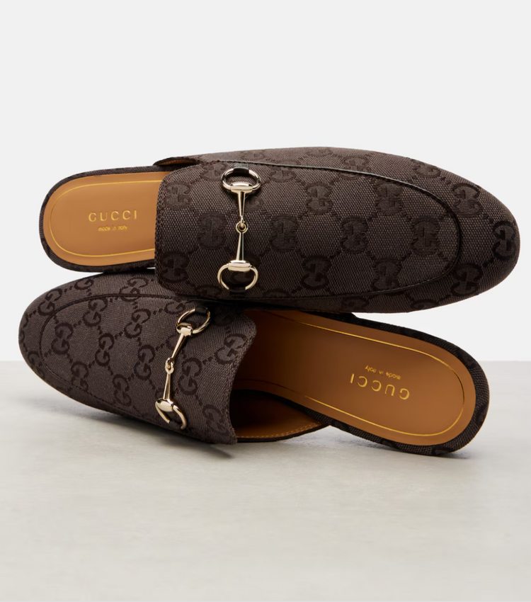 Brown Gucci loafers with horsebit detail on a light gray background