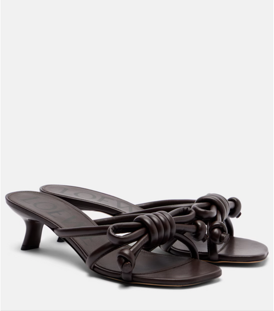 Pair of dark brown high-heeled sandals with knotted design on a white background