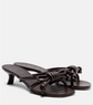 Pair of dark brown high-heeled sandals with knotted design on a white background