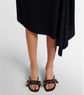 Brown sandals with bow details worn by a person on a light gray background