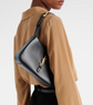 Person wearing a black YSL bag over one shoulder against a neutral background