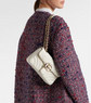 Gucci White quilted handbag with gold chain strap worn by a person in a patterned coat.