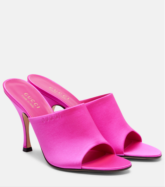 Pair of pink high-heeled Gucci shoes on a white background