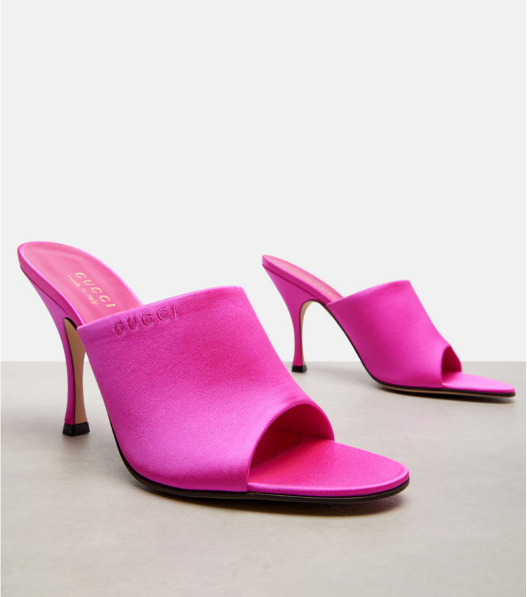 Pair of bright pink high-heeled gucci shoes on a light gray background