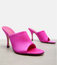 Pair of bright pink high-heeled gucci shoes on a light gray background