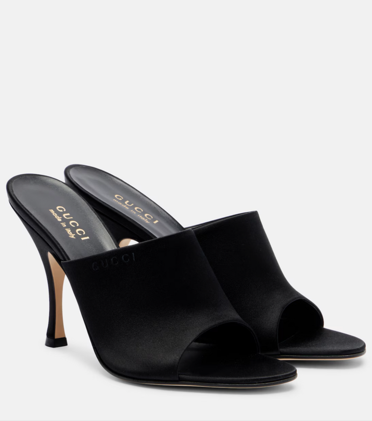 Black high-heeled mules with Gucci logo on a white background