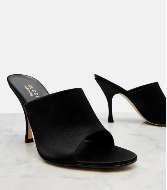 Black high-heeled mules on a light gray background