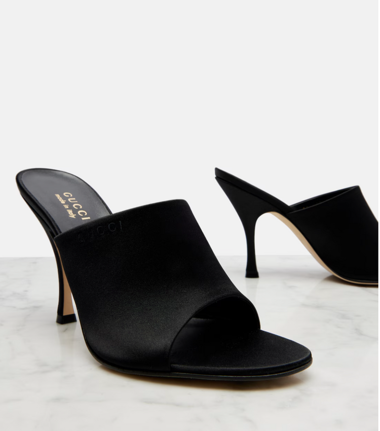 Black high-heeled mules on a light gray background