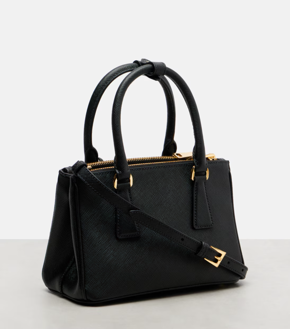 Black handbag with gold accents on a light gray background