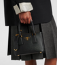 Person holding a black Prada handbag with a white background