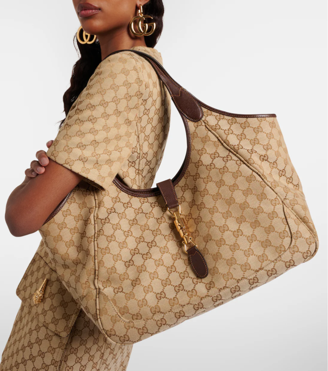 Person wearing a beige patterned outfit with a matching handbag on a white background