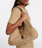 Person holding a Gucci handbag with matching patterned outfit on a white background