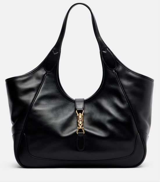 Black leather gucci handbag with gold clasp on a light gray background