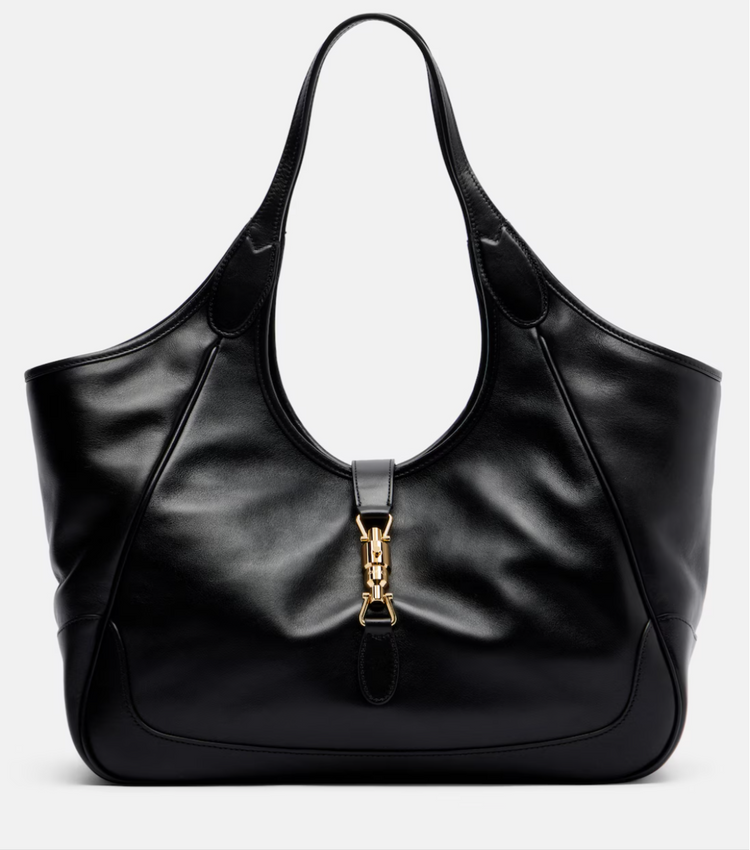 Black leather gucci handbag with gold clasp on a light gray background