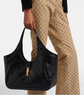 Person holding a black gucci handbag with a visible brand logo, wearing patterned pants.