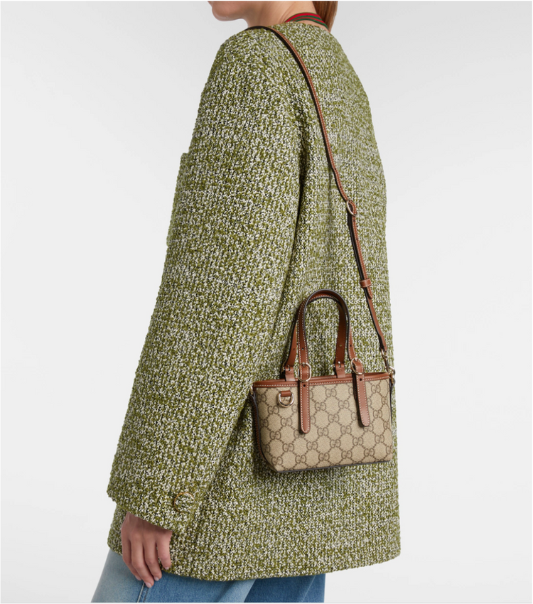 Person wearing a green textured coat with a gucci handbag on a white background